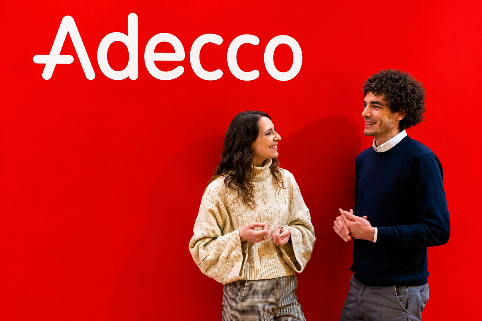 Two ADECCO consultants in front of the red brand wall